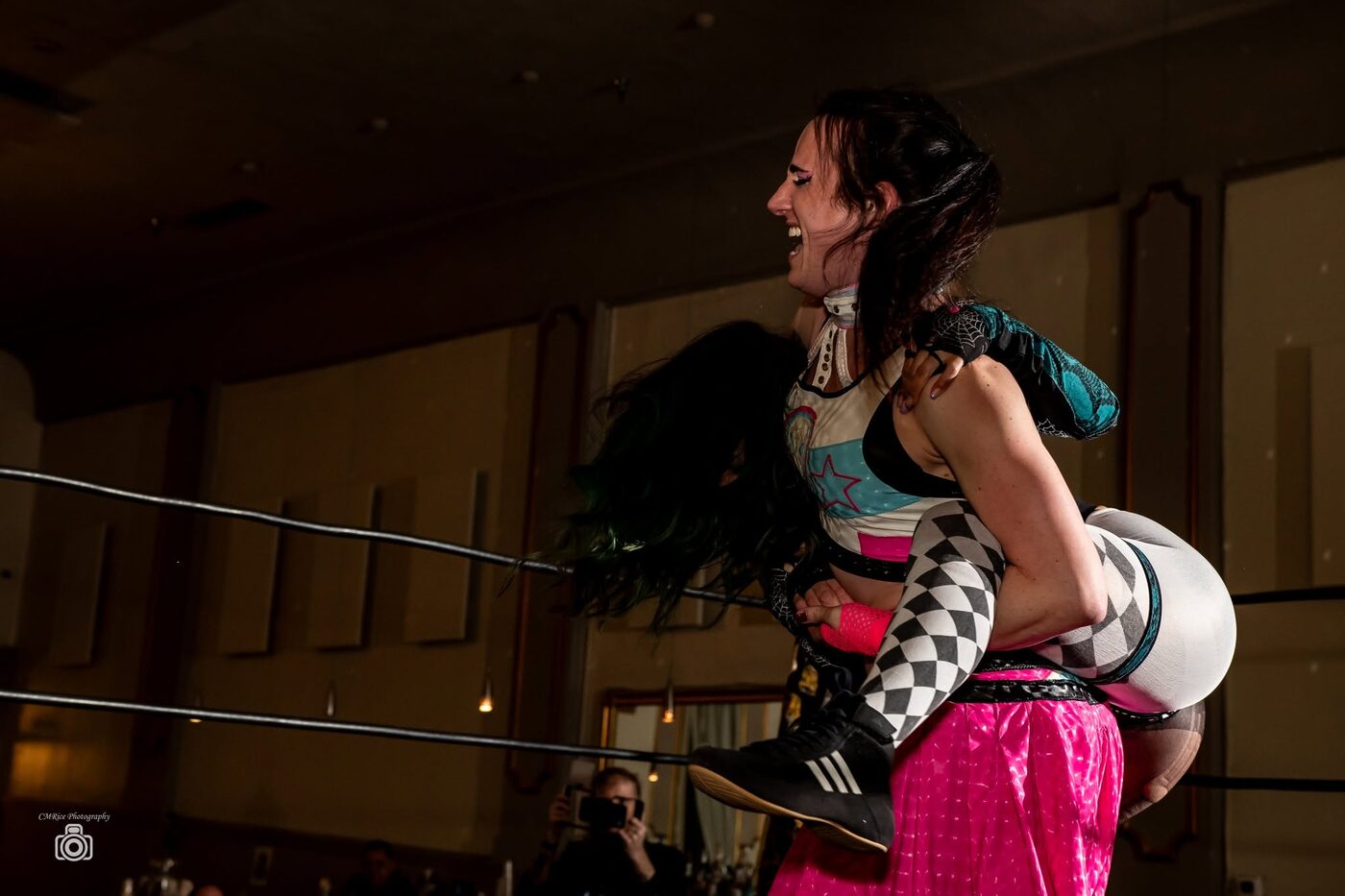 A wrestler carries an opponent across her shoulders